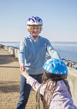 Kız, büyükannesiyle birlikte parkta paten kayıyor. Baharda açık havada.