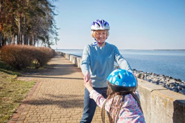 Kız, büyükannesiyle birlikte parkta paten kayıyor. Baharda açık havada.