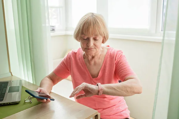 Пожилая женщина проверяет информацию о здоровье с помощью смарт-часов, современного здравоохранения и поддержки — стоковое фото