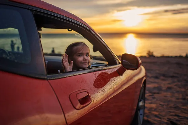 Freedom and family traveler. Girl sitting in the car on the bank of sea after rain