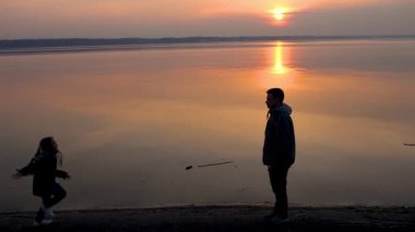 Mutlu çocuk koşuyor ve babasının ellerine doğru koşuyor. Yetişkin ve çocuk siluetleri, aile akşamı.