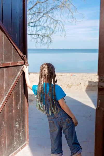 Преждевременная счастливая девочка, открывающая деревянную дверь в солнечную сторону, следуй за мной выстрел, hello summer concept — стоковое фото
