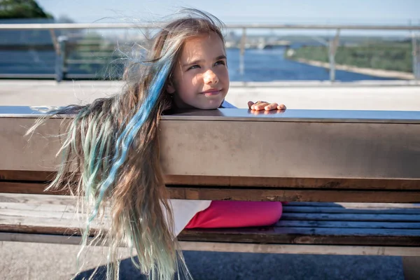Genç esmer, mavi röfleli bir kız köprüdeki nehire bakıyor, yan manzara, yaz günü. — Stok fotoğraf