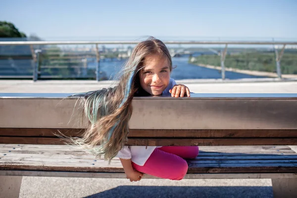 파란색을 띄는 10 대 소녀인 브루넷은 여름날 다리, 사이드 뷰 에서 강을 바라본다. — 스톡 사진