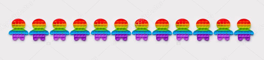 Row of fidget people figures with lgbtq colorful rainbow flag over white background, gay pride concept