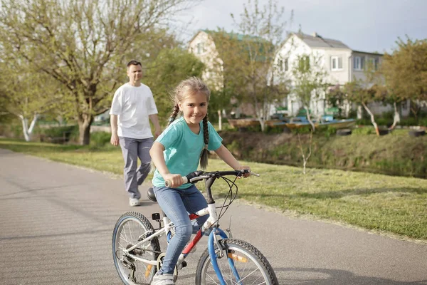 아버지는 어린 딸 이 여름날 마을에서 자전거를 타고 건강에 좋은 생활을 하도록 가르친다 — 스톡 사진