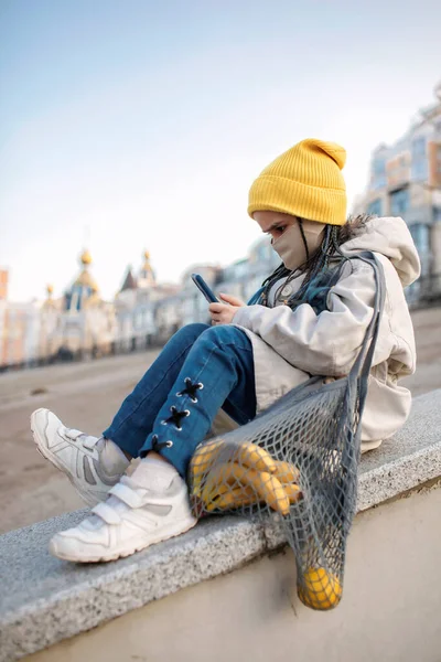 Menina adolescente sentada nas escadas de rua e mensagens de texto com smartphone no caminho de compras — Fotografia de Stock