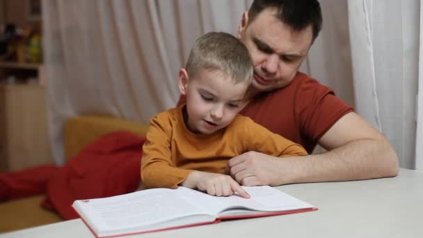 Dzieciak w przedszkolu i jego ojciec czytają razem książkę w domu, Dzień Ojca, nauka i edukacja — Wideo stockowe