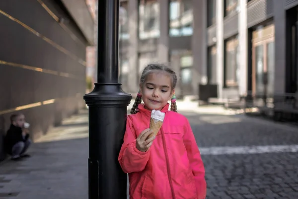 Bella ragazza mangiare gelato in strada su sfondo urbano, divertente ragazzo caramelle, stile di vita esterno — Foto Stock