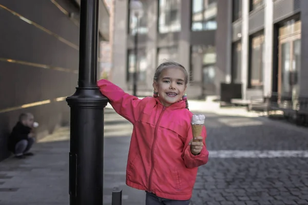 아름다운 소녀 가 도시의 배경 위에서 아이스크림을 먹고 있고, 웃기는 캔디 아이 가 밖에서 생활하고 있습니다. — 스톡 사진