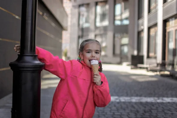 Chica bonita comiendo helado en la calle sobre fondo urbano, niño caramelo divertido, estilo de vida exterior — Foto de Stock