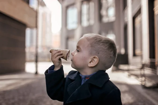 Маленький сладкий мальчик веселиться и держать вафельный конус, как клюв птицы, сладкий десерт, уличная еда — стоковое фото