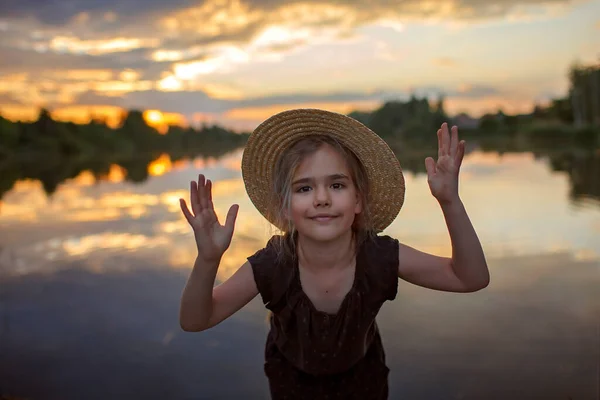 Girl in summer straw hat pulling hand forward to sunset on lake, lifestyle, local travel — Stock Photo, Image