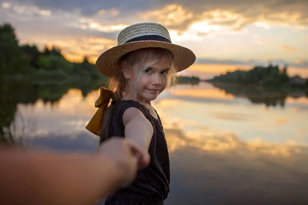 Girl in summer straw hat pulling hand forward to sunset on lake, lifestyle, local travel — Stock Photo, Image