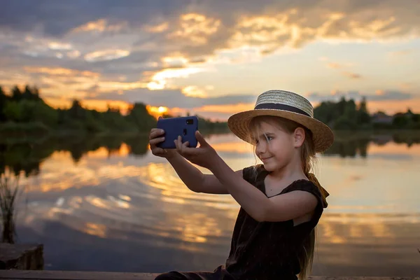 Lány nyári szalma kalap csinál selfie mobiltelefon naplementekor tavon, életmód, helyi utazás — Stock Fotó