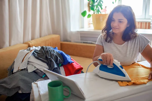 Mom watches video on tablet and ironing things at the same time, social media addiction