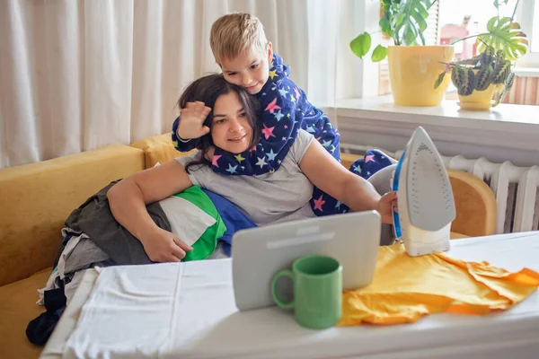 Mama i syn rozmawiają z krewnymi na tablecie, wykonując prace domowe, internet i dystans społeczny — Zdjęcie stockowe