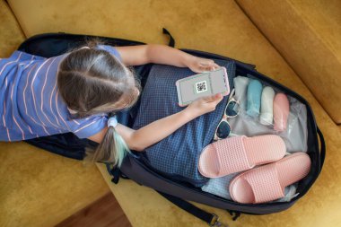 Bavulun yanında oturan kız tatil için hazırlanıyor ve aşıya dayanıklı bir mesaj veriyor.