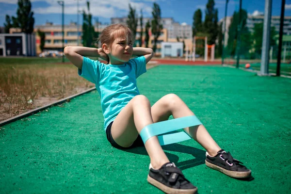 Девочка-подросток делает упражнения с фитнес-группой на общественной площадке в городе, спорт — стоковое фото