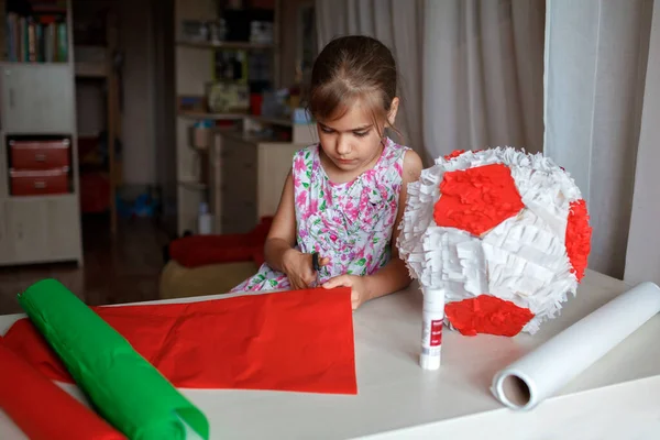 Çocuk kullanılmış kutudan ve renkli kağıttan kartonla pinyata yapıyor. Doğum günü partisinde süsleme yapıyor. — Stok fotoğraf