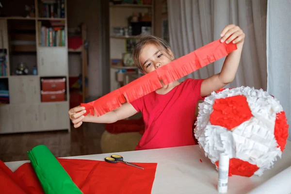Çocuk kullanılmış kutudan ve renkli kağıttan kartonla pinyata yapıyor. Doğum günü partisinde süsleme yapıyor. — Stok fotoğraf