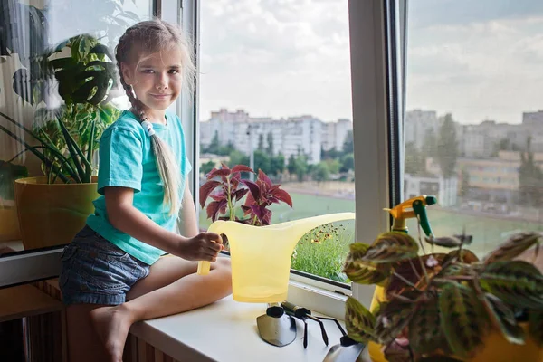 Linda chica ayudando a cuidar de las plantas caseras en la ventana del balcón, concepto de padres de plantas —  Fotos de Stock