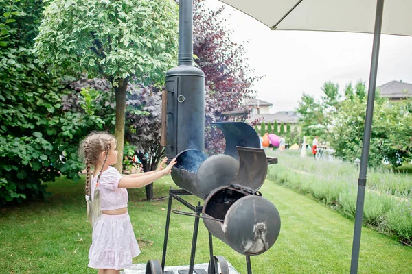 Smoker grill in home backyard, family patio, outdoor bbq party on open air, green garden background