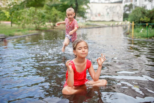 Cute kids jumping and swimming in the puddles after warm summer rain, happy childhood — Stock Photo, Image