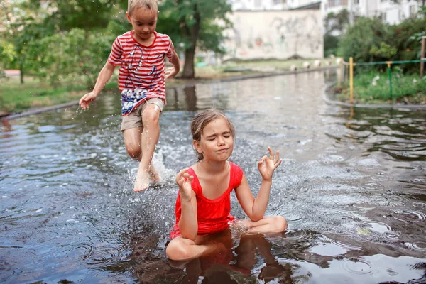 Copii drăguți sărind și înotând în bălți după ploaie caldă de vară, copilărie fericită — Fotografie, imagine de stoc