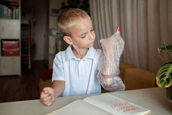 Vänsterhänt pojke sätta sin vänstra hand i plast handske för att undvika röriga, internationella vänster-hander dag — Stockfoto