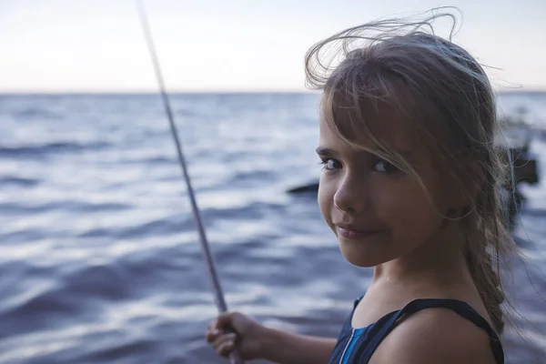 Girl in swimming wear fishing from sea beach in early morning, blue hours, active weekend, camping — Stock Photo, Image