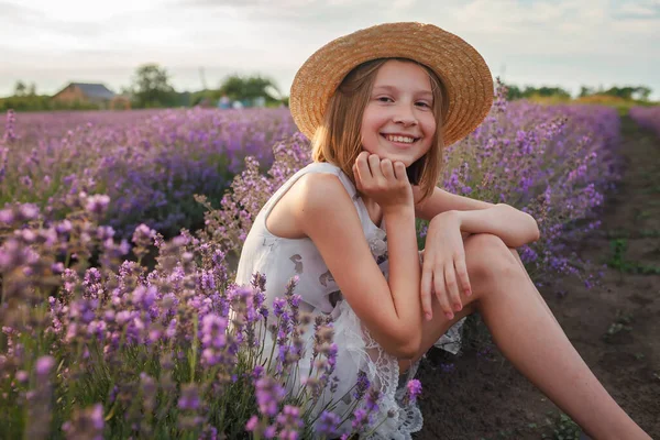 Dreamy teenager girl in straw hat sits in lavender field. Beauty of nature, summer lifestyle — Stock Photo, Image