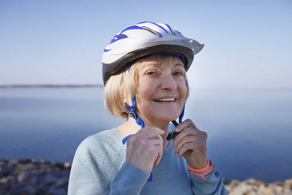 Старшая женщина надевает защитный шлем перед катанием на роликах по природе, психическому и физическому здоровью Лицензионные Стоковые Фото