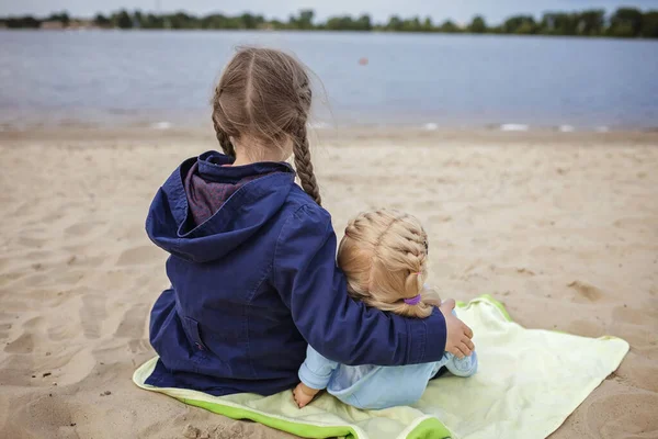 Одинокая обожаемая восьмилетняя девочка, играющая с дочкой на осеннем пляже, мать и дочь — стоковое фото