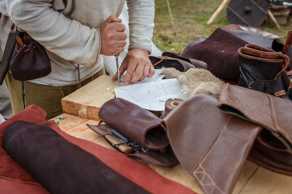 Craft shoemaker demonstrates shoes, tools and leather at cobbler workplace on festival workshop