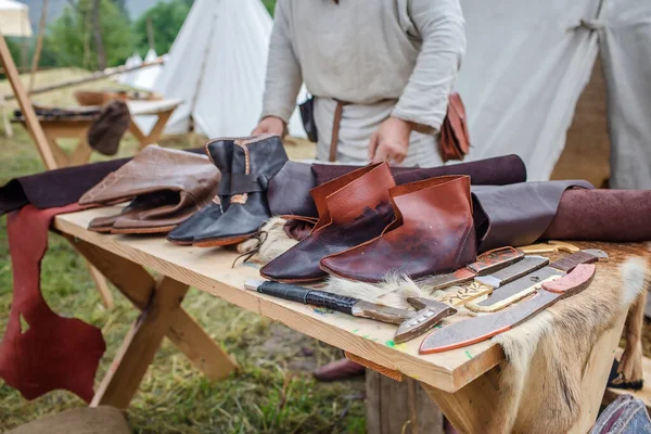 Craft shoemaker demonstrates shoes, tools and leather at cobbler workplace on festival workshop