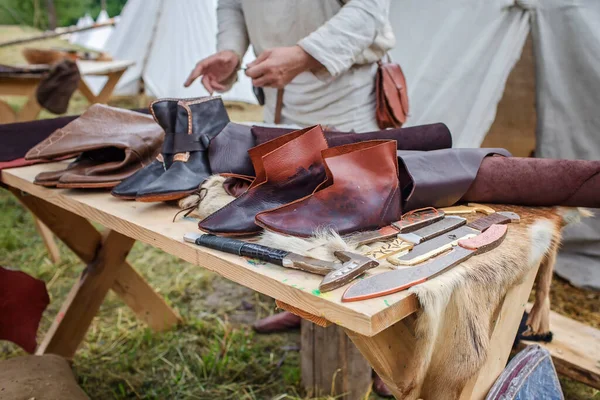 Craft shoemaker demonstrates shoes, tools and leather at cobbler workplace on festival workshop