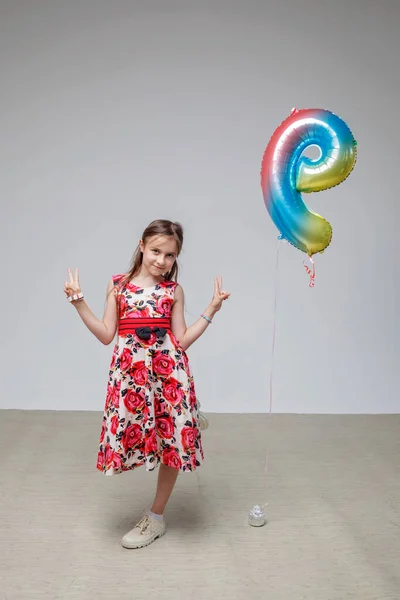 Девушка с длинными волосами в праздничном платье танцует на белом фоне, празднование дня рождения, студия — стоковое фото