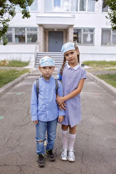 Torniamo a scuola. I fratelli con zaini in maschere mediche rimangono vicino alle porte prima del primo giorno offline — Foto Stock