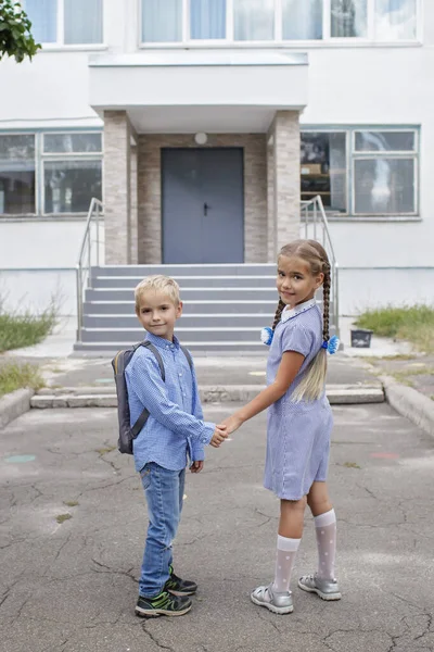 Torniamo a scuola. Fratelli con zaini che stanno vicino alle porte della scuola prima del loro primo giorno offline — Foto Stock
