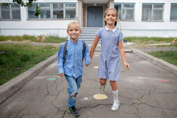 Torniamo a scuola. Fratelli con zaini che scappano dalla scuola dopo il loro primo giorno offline — Foto Stock