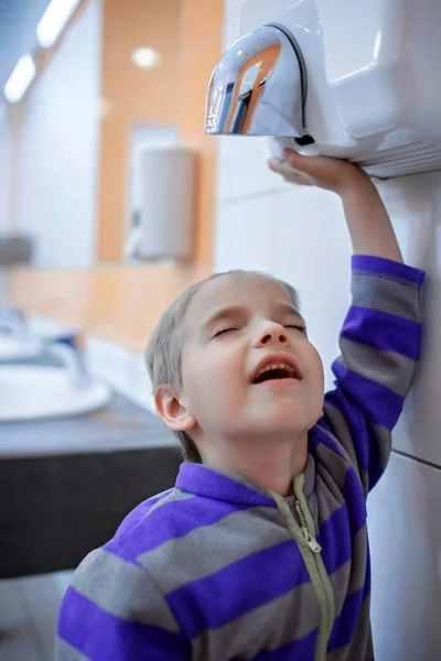 Jongen droogt zijn hand in het toilet in het winkelcentrum, persoonlijke hygiëne in de openbare ruimte, gezondheidszorg, plezier — Stockfoto