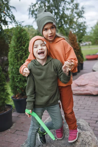 유행하는 모자를 쓰고 후드를 쓴 아이들은 공원에서 재미를 보고, 가을 취향, 가을 스타일, 어린이 패션을 즐긴다 — 스톡 사진