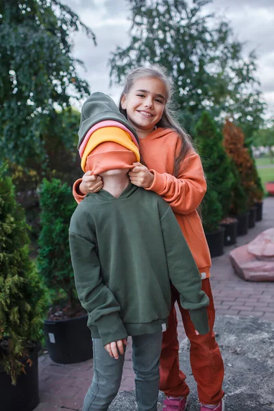 Niños con sombreros y sudaderas de moda que se divierten en el parque, vibraciones de otoño, estilo de belleza otoñal, moda infantil — Foto de Stock