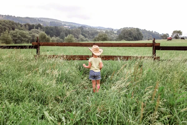 Local vacation, stay safe, stay home. Little girl in cowboy hat playing in western in the farm — Stock Photo, Image