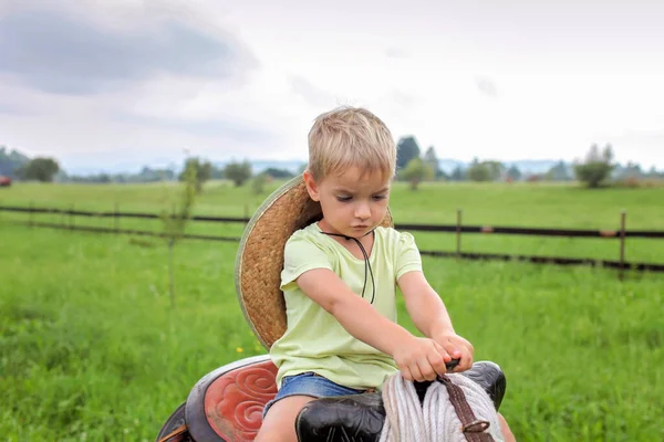 Lokale vakantie, blijf veilig, blijf thuis. Kleine jongen in cowboy hoed spelen in het westen in de boerderij — Stockfoto