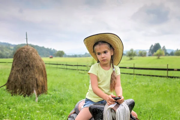 Local vacation, stay safe, stay home. Little girl in cowboy hat playing in western in the farm