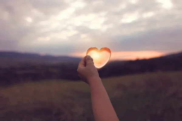 A glass heart with sun inside over cloudy twilight sky — Stock Photo, Image
