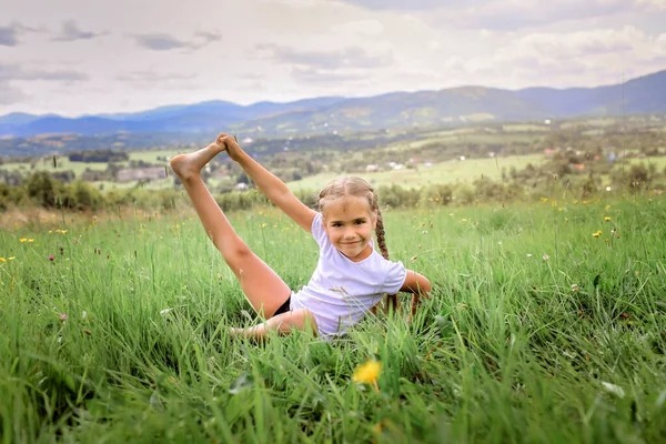 Attractive girl doing her morning exercises on the top of the mountains in summer nature — Stock Photo, Image