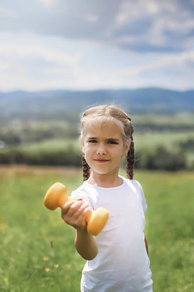 Girl doing her morning exercises with dumbbell on the top of the mountains in summer — Stock Photo, Image